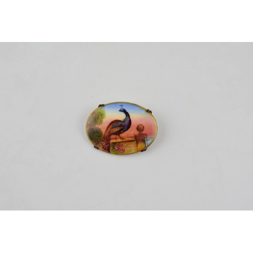 484 - Hand painted porcelain miniature brooch depicting a peacock standing on a wall at sunset. Possibly M... 