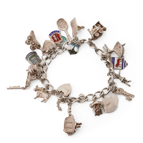 220 - Silver charm bracelet with various charms to include a tennis racket, a film camera, a train, a lady... 