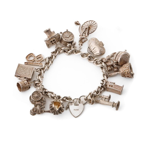 223 - Silver charm bracelet with various charms to include a a bible, a purse, a bell, a telephone and oth... 