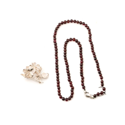 308 - A silver floral brooch with a garnet bead necklace on silver clasp, 57cm long (2).