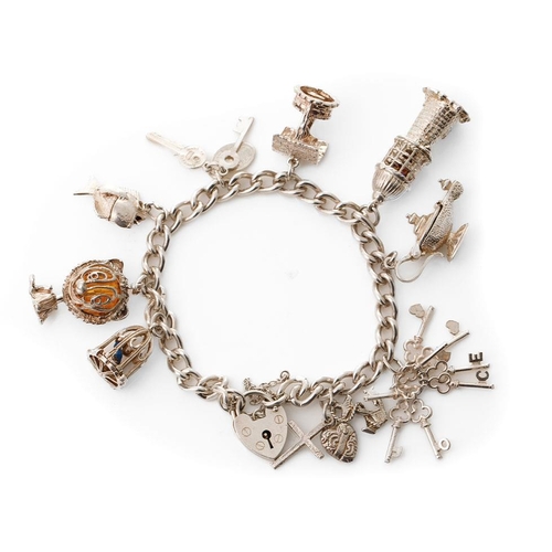 331 - Silver charm bracelet with charms to include a wishing well, a lighthouse, a globe, a bird cage and ... 