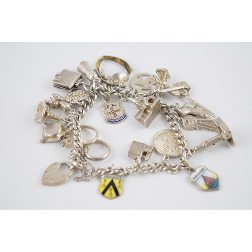 214 - Silver charm bracelet with various charms to include an ice skating boot, rings, a lighthouse and ot... 