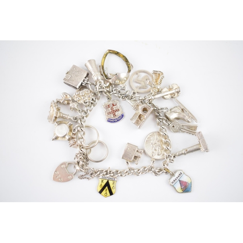 214 - Silver charm bracelet with various charms to include an ice skating boot, rings, a lighthouse and ot... 