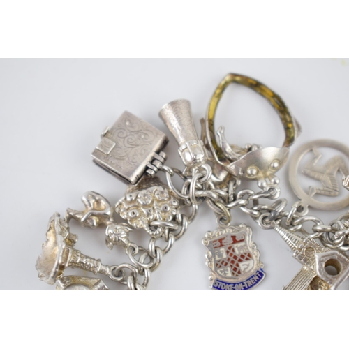 214 - Silver charm bracelet with various charms to include an ice skating boot, rings, a lighthouse and ot... 