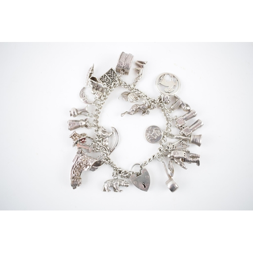 215 - Silver charm bracelet with various charms to include an astronaut, a pair of binoculars, a bell and ... 