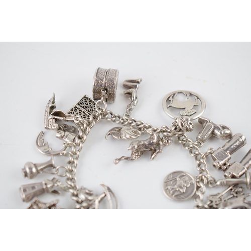 215 - Silver charm bracelet with various charms to include an astronaut, a pair of binoculars, a bell and ... 