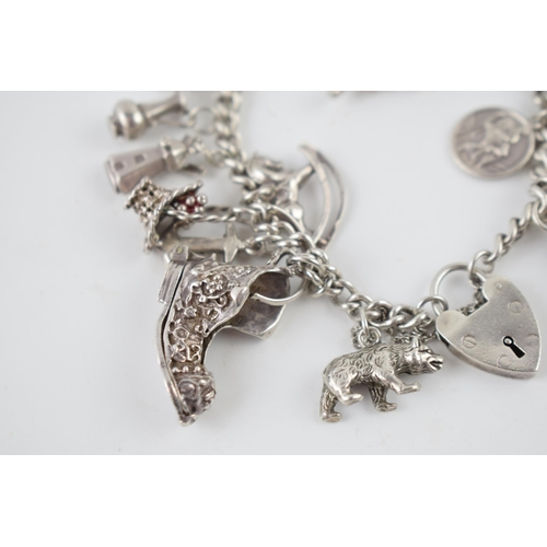 215 - Silver charm bracelet with various charms to include an astronaut, a pair of binoculars, a bell and ... 