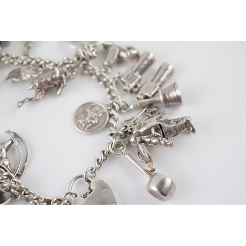 215 - Silver charm bracelet with various charms to include an astronaut, a pair of binoculars, a bell and ... 