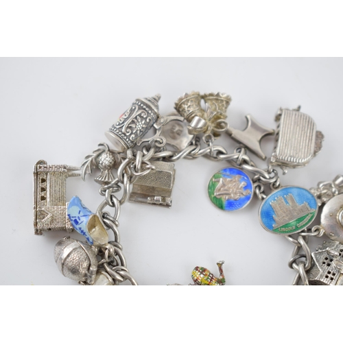 216 - Silver charm bracelet with various charms to include a house, an anvil, a toaster, a book and others... 