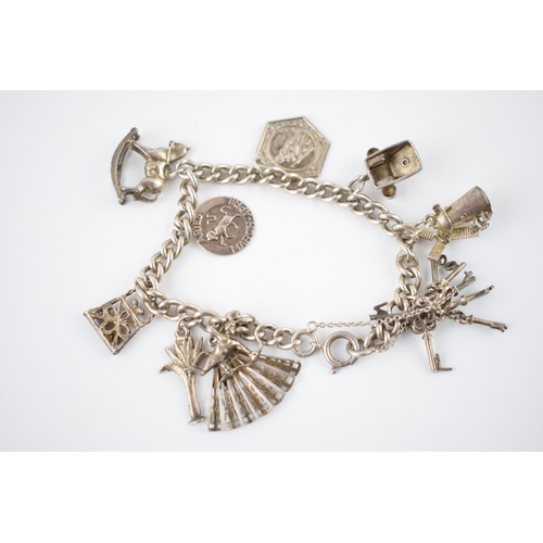 217 - Silver charm bracelet with various charms to include Cupid, a fan, a rocking horse and others, 37.5 ... 