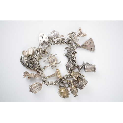 218 - Silver charm bracelet with various charms to include a tankard, a fan, a crab, a bull and others, 69... 