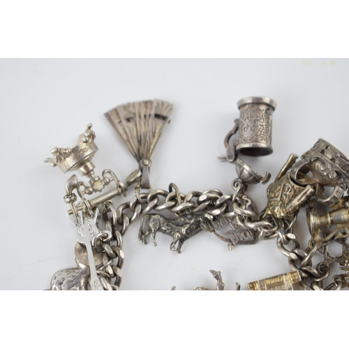 218 - Silver charm bracelet with various charms to include a tankard, a fan, a crab, a bull and others, 69... 