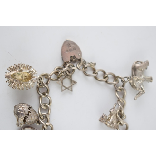 219 - Silver charm bracelet with various charms to include a hedgehog, a pair of rabbits, a well and other... 