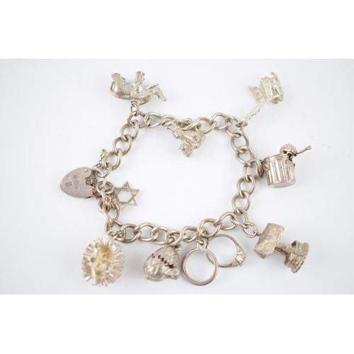 219 - Silver charm bracelet with various charms to include a hedgehog, a pair of rabbits, a well and other... 