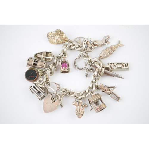 221 - Silver charm bracelet with various charms to include an aeroplane, a tram, a robot, a miner's lamp a... 