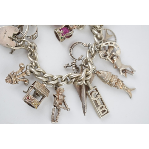 221 - Silver charm bracelet with various charms to include an aeroplane, a tram, a robot, a miner's lamp a... 