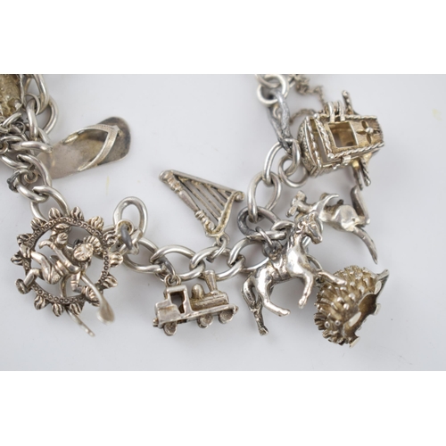 222 - Silver charm bracelet with various charms to include a poodle, a hedgehog, a shell, a carriage and o... 