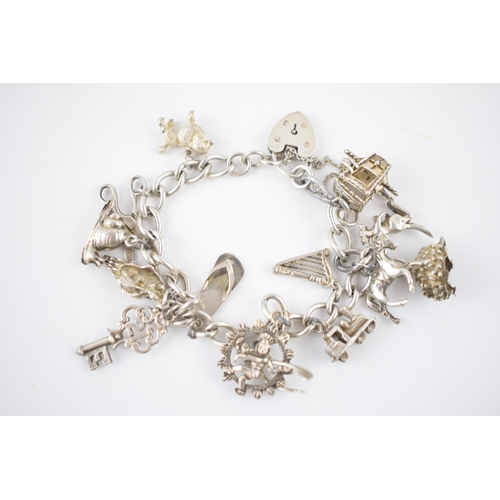 222 - Silver charm bracelet with various charms to include a poodle, a hedgehog, a shell, a carriage and o... 