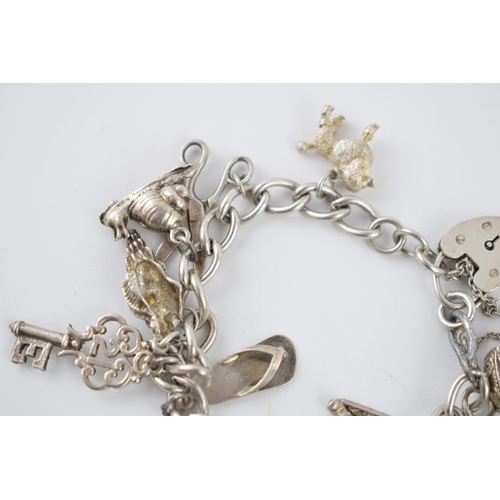 222 - Silver charm bracelet with various charms to include a poodle, a hedgehog, a shell, a carriage and o... 