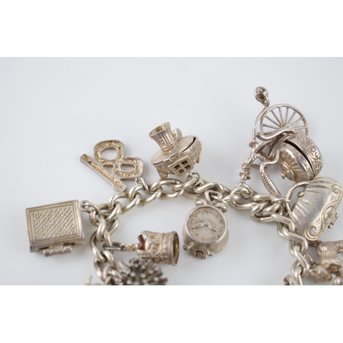 223 - Silver charm bracelet with various charms to include a a bible, a purse, a bell, a telephone and oth... 