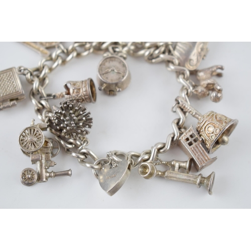 223 - Silver charm bracelet with various charms to include a a bible, a purse, a bell, a telephone and oth... 