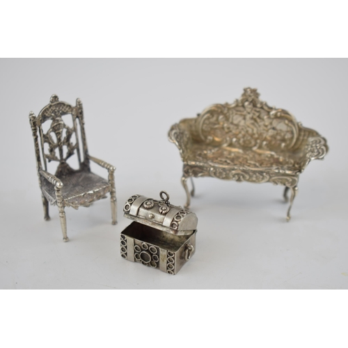 152 - Silver miniature dolls house sofa with cherub decoration, Birmingham 1962, a silver chair and a trun... 