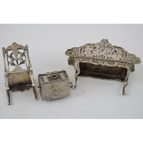 152 - Silver miniature dolls house sofa with cherub decoration, Birmingham 1962, a silver chair and a trun... 