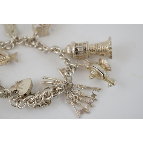 331 - Silver charm bracelet with charms to include a wishing well, a lighthouse, a globe, a bird cage and ... 