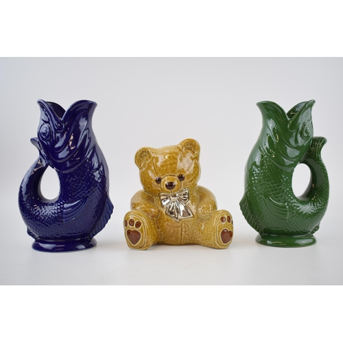 141 - A trio of Wade Ceramics to include 2 Gluggle jugs in green and blue, 22cm tall, with a teddy bear mo... 