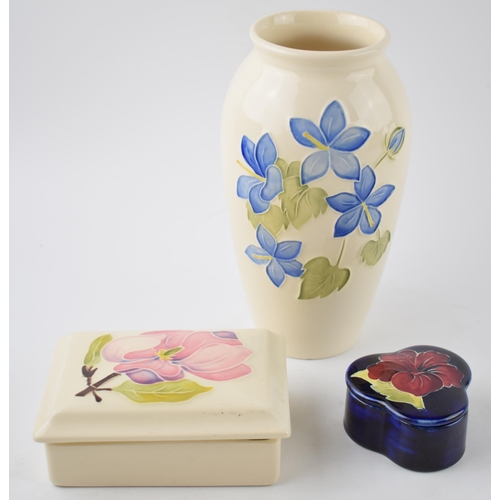 119A - A trio of Moorcroft items to include a blue floral vase, 19cm tall, a Hibscus on magnolia trinket an... 