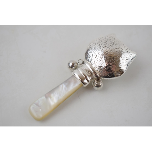 233 - Sterling silver baby rattle with mother of pearl handle in the form of a cat's head, 7.5cm long.