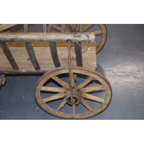 284 - An antique dog cart. Sitting on four hand-made wheels. 100cm x 60cm x 58cm.