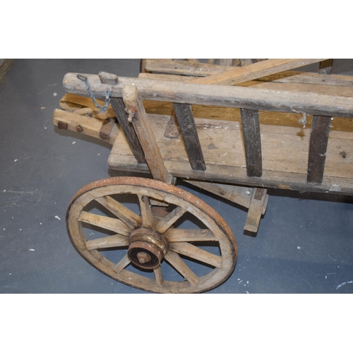 284 - An antique dog cart. Sitting on four hand-made wheels. 100cm x 60cm x 58cm.