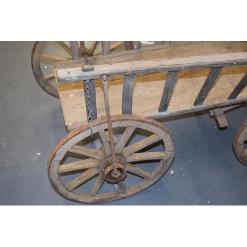 284 - An antique dog cart. Sitting on four hand-made wheels. 100cm x 60cm x 58cm.