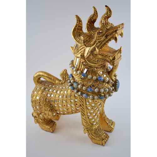 309 - An Oriental style lion with beaded necklace and inlaid mirrors. Height 46cm.