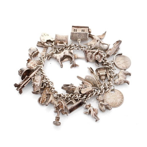 496 - Silver charm bracelet with a collection of charms to include London Bridge, a Bobby's helmet, a plan... 