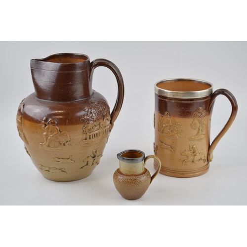 200 - A trio of stoneware items to include a silver rimmed Doulton Lambeth tankard, a large pouring jug, p... 