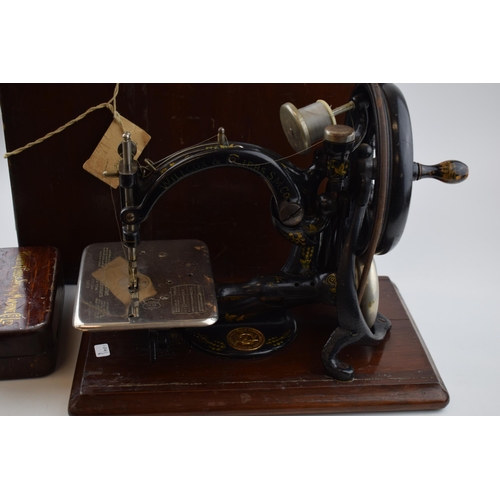 261 - Willcox & Gibbs sewing machine, hand propelled, with wooden carry case / box, with a box of accessor... 