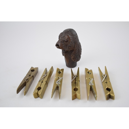 278 - A collection of 6 brass clothes pegs, working order, with a carved wooden stick handle in the form o... 