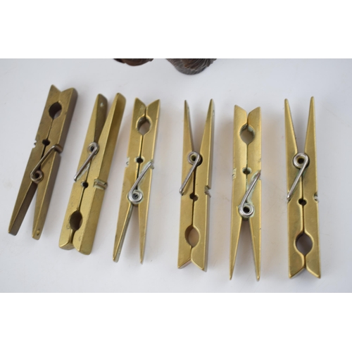 278 - A collection of 6 brass clothes pegs, working order, with a carved wooden stick handle in the form o... 