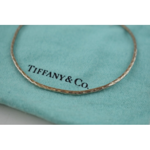 458 - Tiffany & Co hammered silver bangle, with original purchase receipt, 5.0 grams.