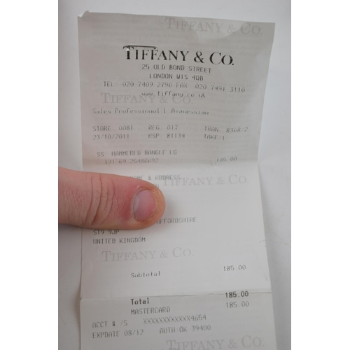 458 - Tiffany & Co hammered silver bangle, with original purchase receipt, 5.0 grams.