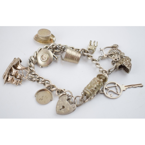 469 - Silver charm bracelet with charms to include a tankard, a key, a bucket and others, 52.6 grams.