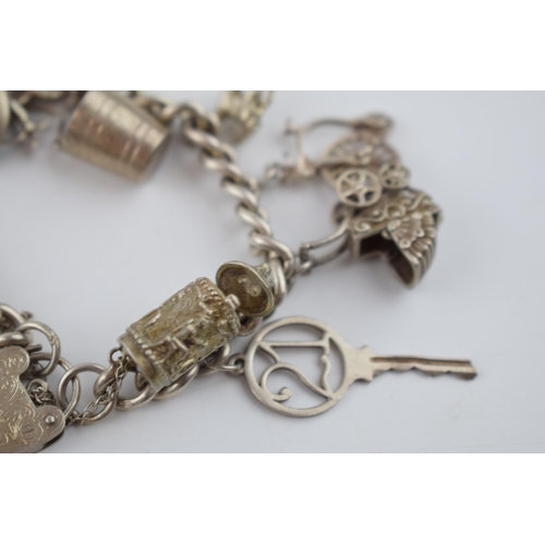 469 - Silver charm bracelet with charms to include a tankard, a key, a bucket and others, 52.6 grams.