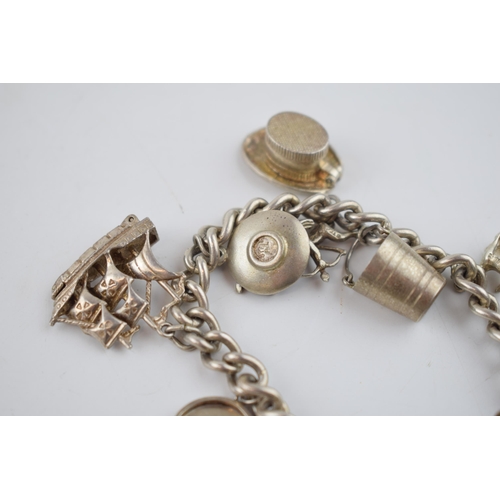 469 - Silver charm bracelet with charms to include a tankard, a key, a bucket and others, 52.6 grams.