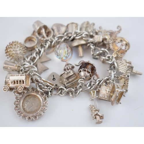 470 - Silver charm bracelet with charms to include a teapot, a crown, a knight and others, 96.9 grams.