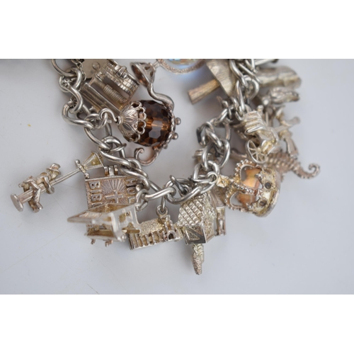 470 - Silver charm bracelet with charms to include a teapot, a crown, a knight and others, 96.9 grams.