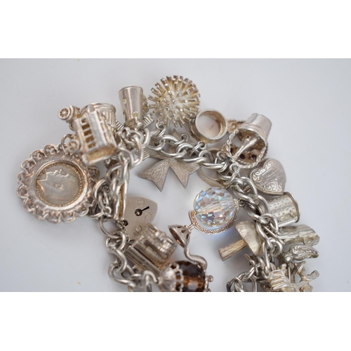 470 - Silver charm bracelet with charms to include a teapot, a crown, a knight and others, 96.9 grams.