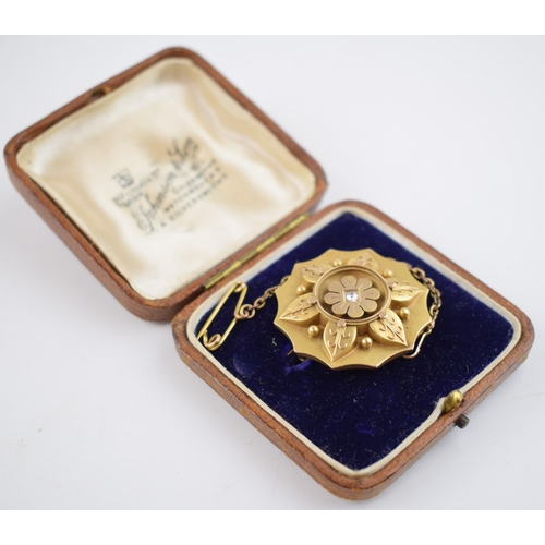 485 - 15ct gold brooch, in the form of a flower, with central diamond and locket reverse, with metal safet... 