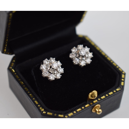 583 - Pair of diamond daisy style earrings set in white gold.  Not hallmarked but believed to be 18ct.  To... 